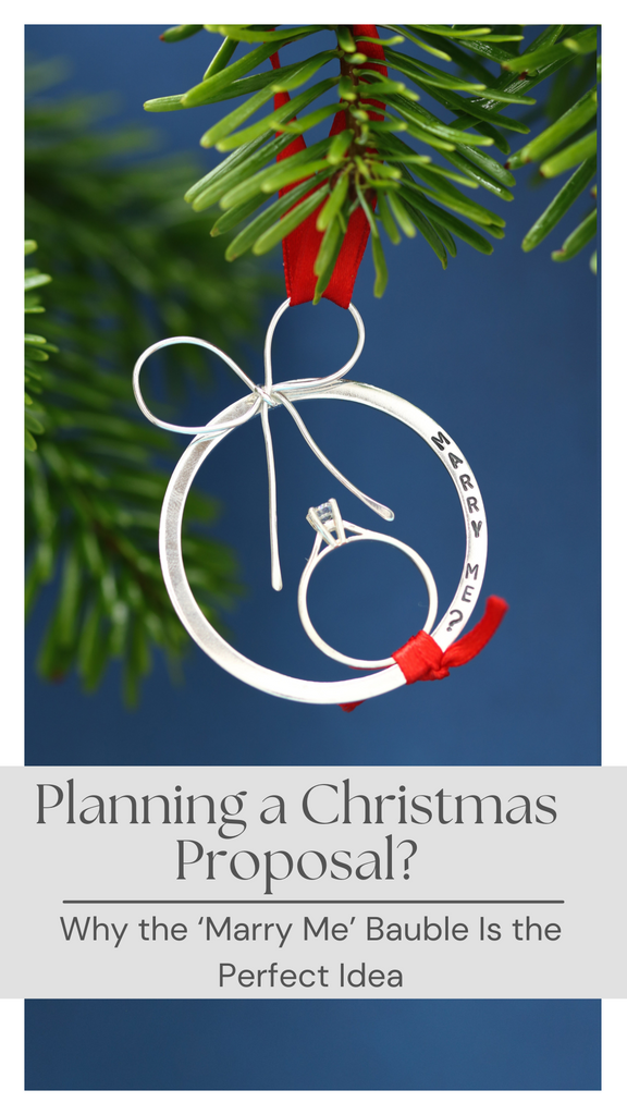 Handmade sterling silver proposal bauble with engagement ring tied on red ribbon, hanging on Christmas tree – perfect Christmas proposal idea.