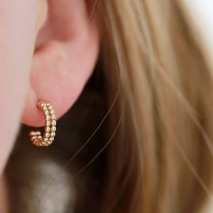 Small 9ct gold hoop earrings modelled close to the ear, demonstrating their comfortable fit and perfect gifting appeal.