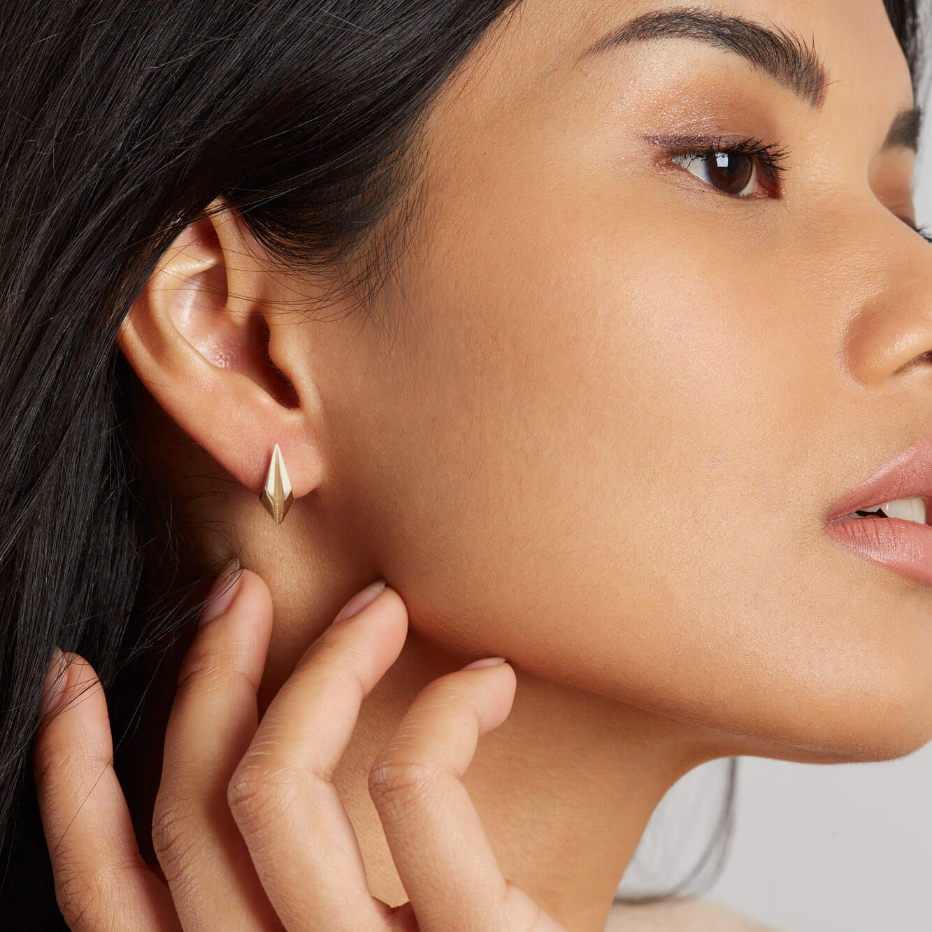 Gold geometric earrings modelled close up, timeless art deco gift for her.