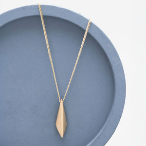 9ct gold pendant necklace with geometric kite-shaped solid gold pendant displayed on a deep blue dish