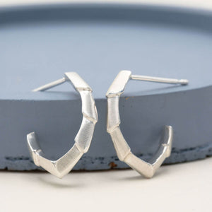 Half hoop earrings in polished sterling silver, showing the open geometric design and sculptural shape