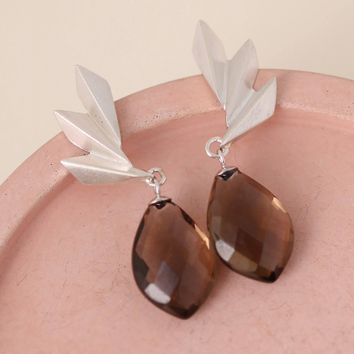 Art deco statement earrings displayed on a soft pink dish with teardrop smoky quartz stones; perfect anniversary or birthday gift.