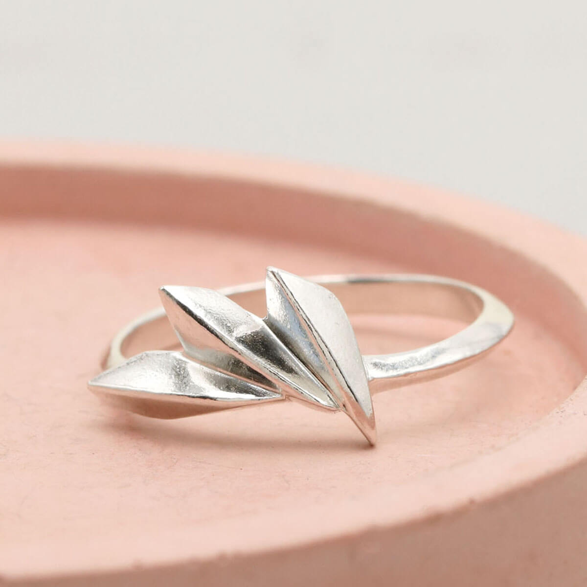 Sterling silver fan ring with concertina geometric design, handmade Art Deco silver ring photographed on a pink dish