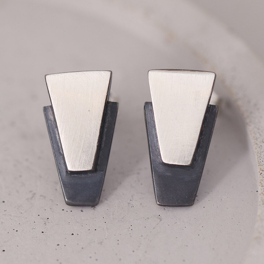 Black stud earrings for women displayed on a grey dish, handcrafted in sterling silver with oxidised centres, ideal birthday or anniversary gift.