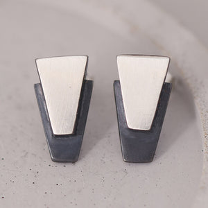 Black stud earrings for women displayed on a grey dish, handcrafted in sterling silver with oxidised centres, ideal birthday or anniversary gift.