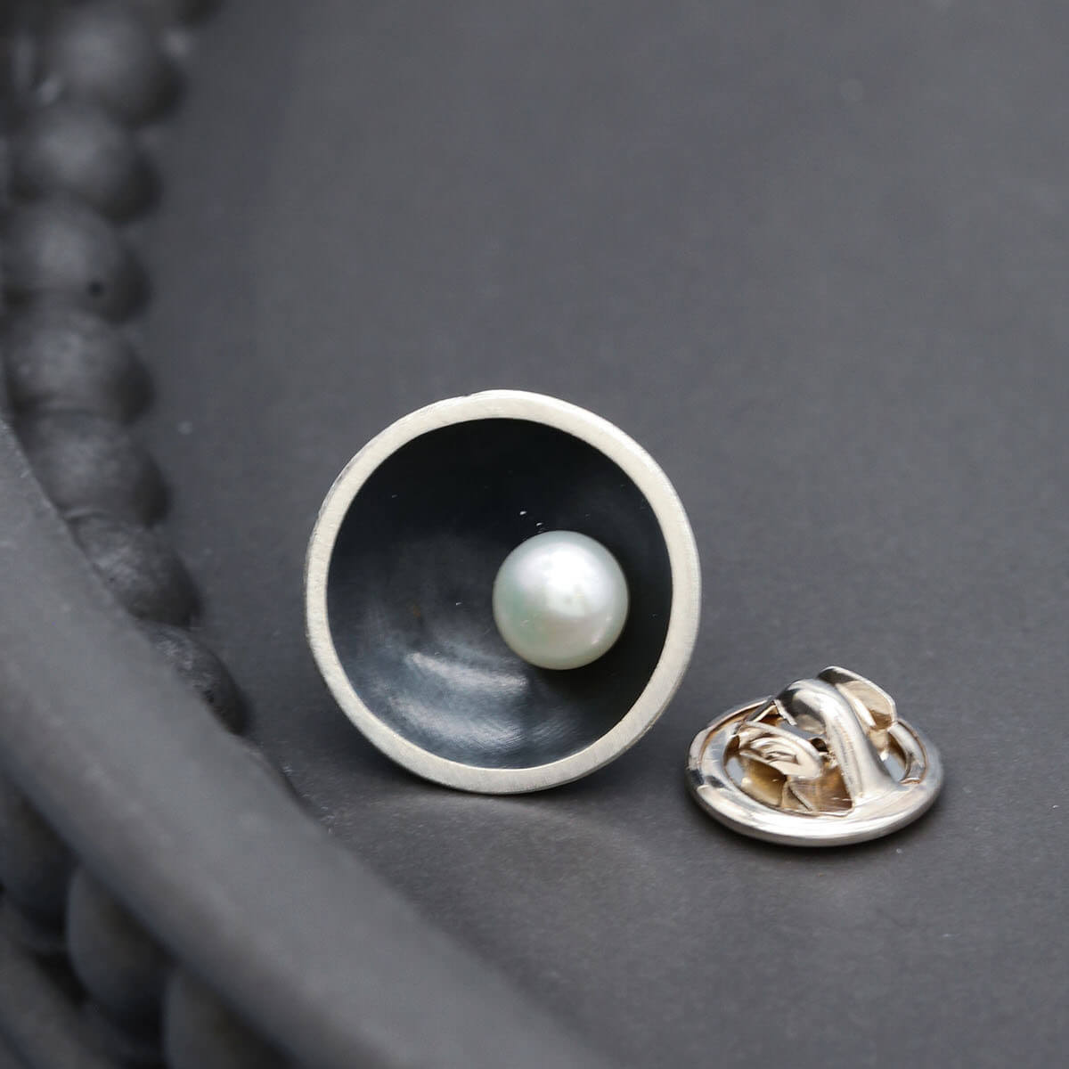 Handmade black pearl tie pin displayed on a dark grey background, showcasing the elegant Art Deco inspired design.