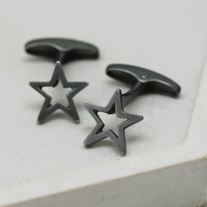 Close-up of black oxidised Star cufflinks with matte finish on a grey dish – striking cufflinks perfect as a graduation gift for son.