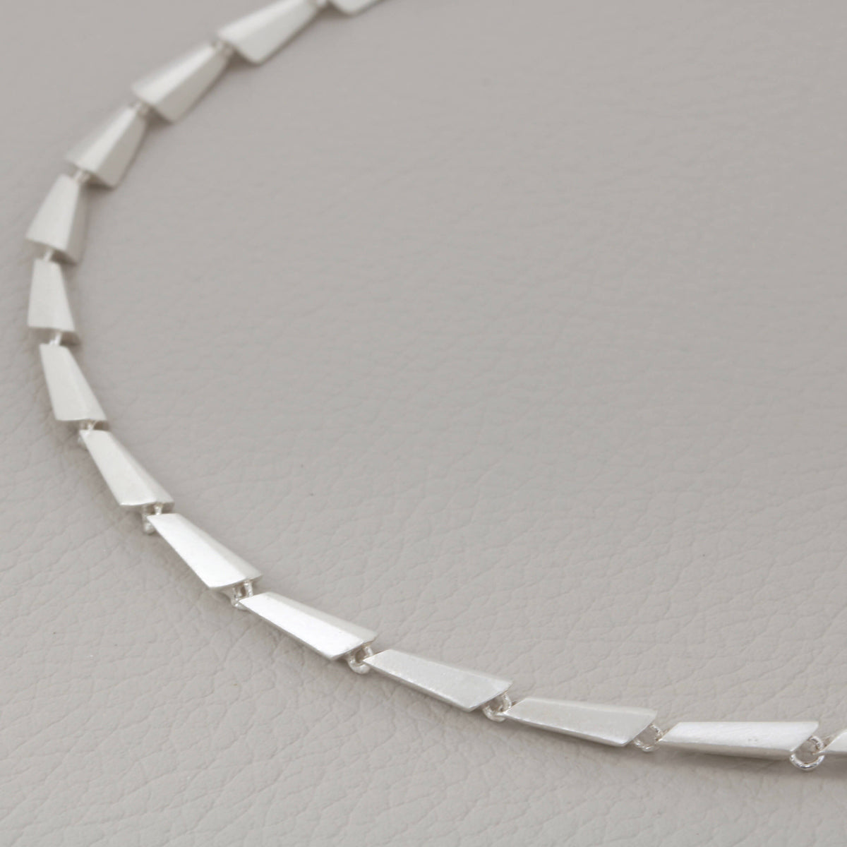 Close-up of a sterling silver link necklace on a grey background, showcasing the Art Deco pattern and modern geometric design — a perfect contemporary necklace gift for her.