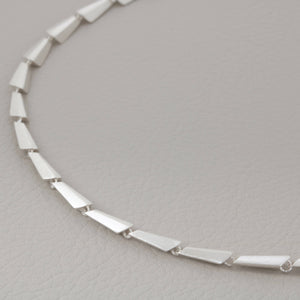 Close-up of a sterling silver link necklace on a grey background, showcasing the Art Deco pattern and modern geometric design — a perfect contemporary necklace gift for her.
