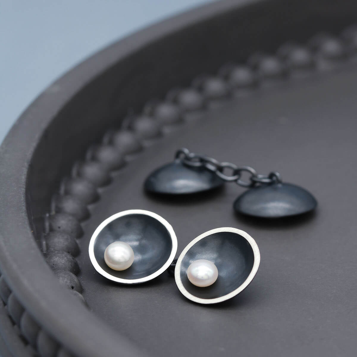 Detailed view of double-sided pearl cufflinks highlighting the contrast between oxidised silver and lustrous pearls.