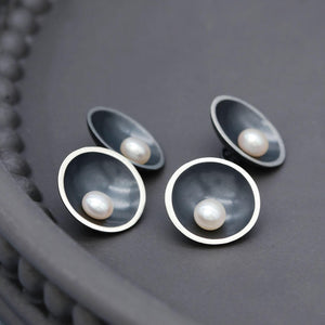 Black double-sided pearl cufflinks featuring freshwater pearls on both sides and a sterling silver chain connection.