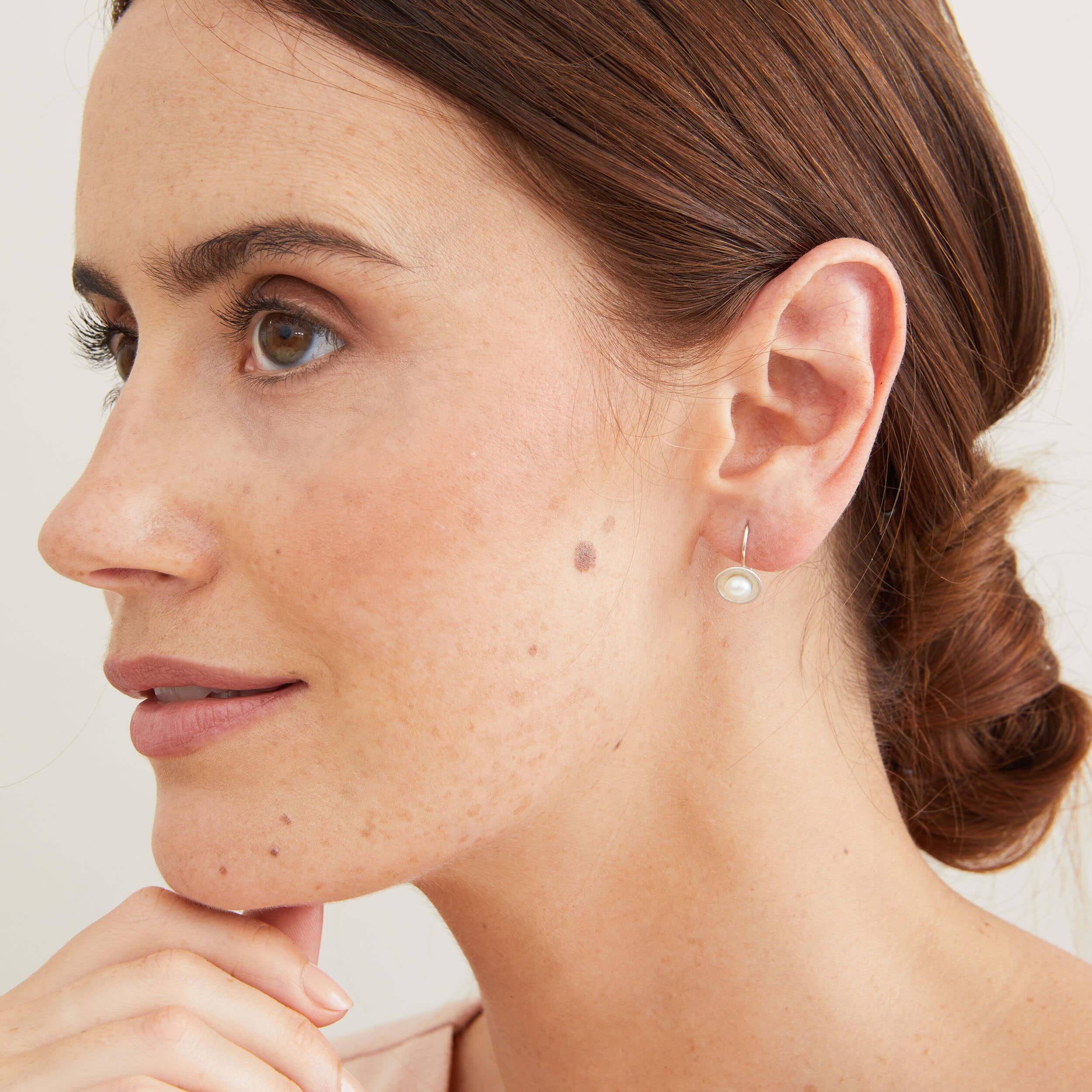 Model wearing handmade sterling silver drop freshwater pearl earrings with genuine freshwater pearls and polished silver settings. 