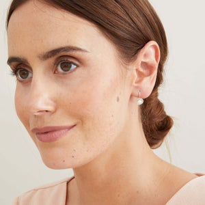 Sterling silver freshwater pearl drop earrings worn on the ear, showing their elegant floating profile created by the fixed hook fittings. 
