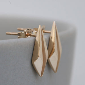 Close up of gold geometric earrings on pale grey, elegant art deco jewellery for bridal gifts.