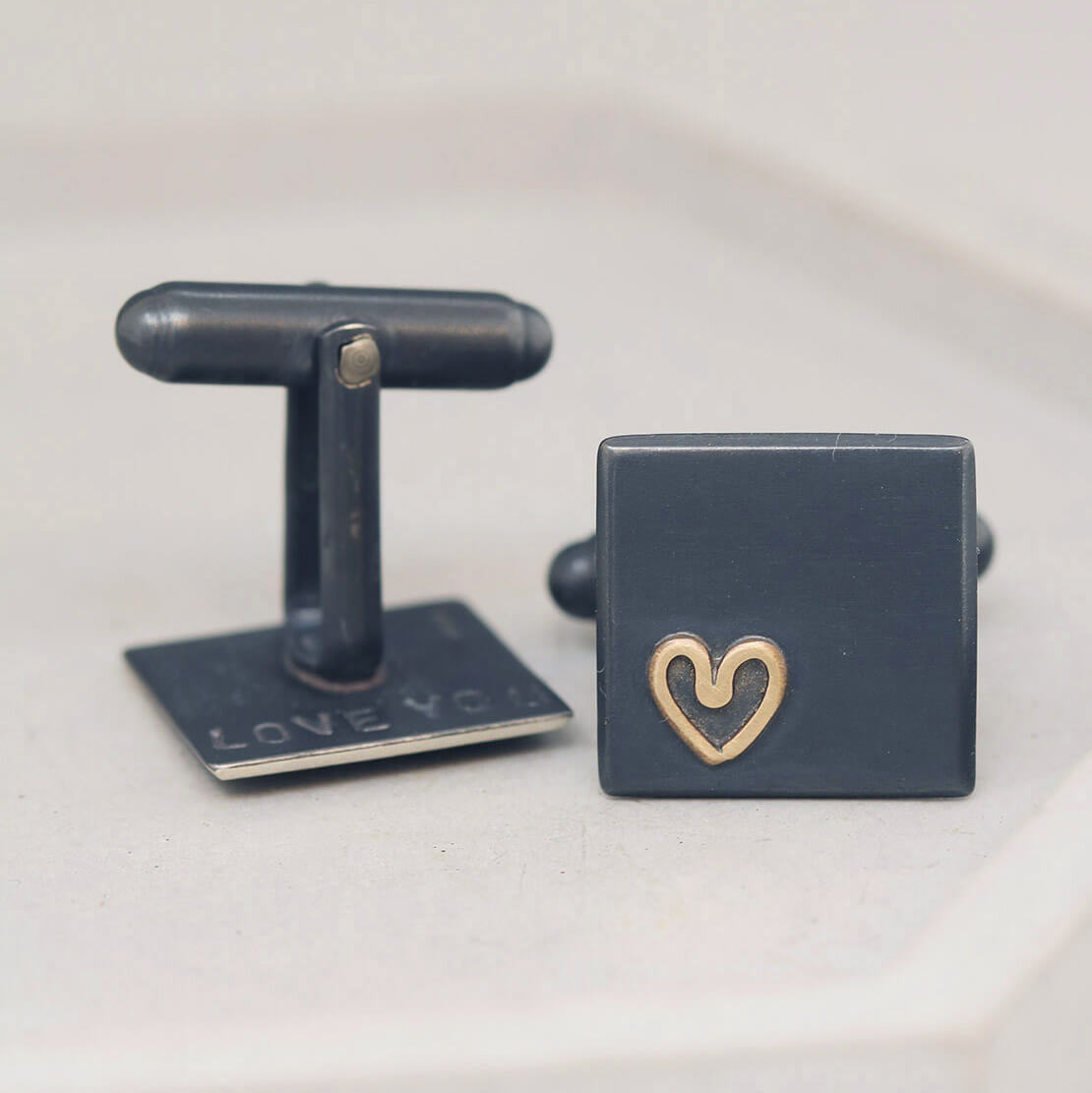 Gold heart Groom wedding cufflinks on grey dish, elegant silver design ideal as special anniversary gifts for husband.