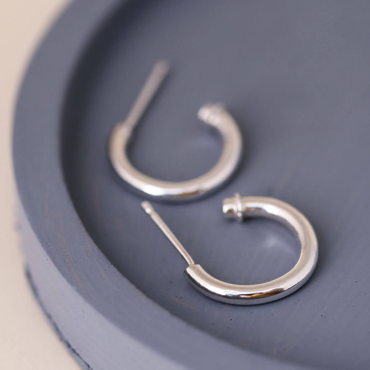 Silver hoop earrings without charm on a blue dish, classic sterling silver hoops with a minimalist finish