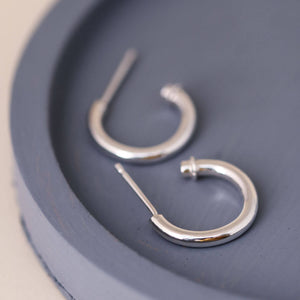 Silver hoop earrings without charm on a blue dish, classic sterling silver hoops with a minimalist finish