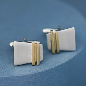 Silver and gold cufflinks resting on deep blue surface with clear view of gold pinstripe; premium luxury cufflinks ideal for groomsmen gifts or professional wear.