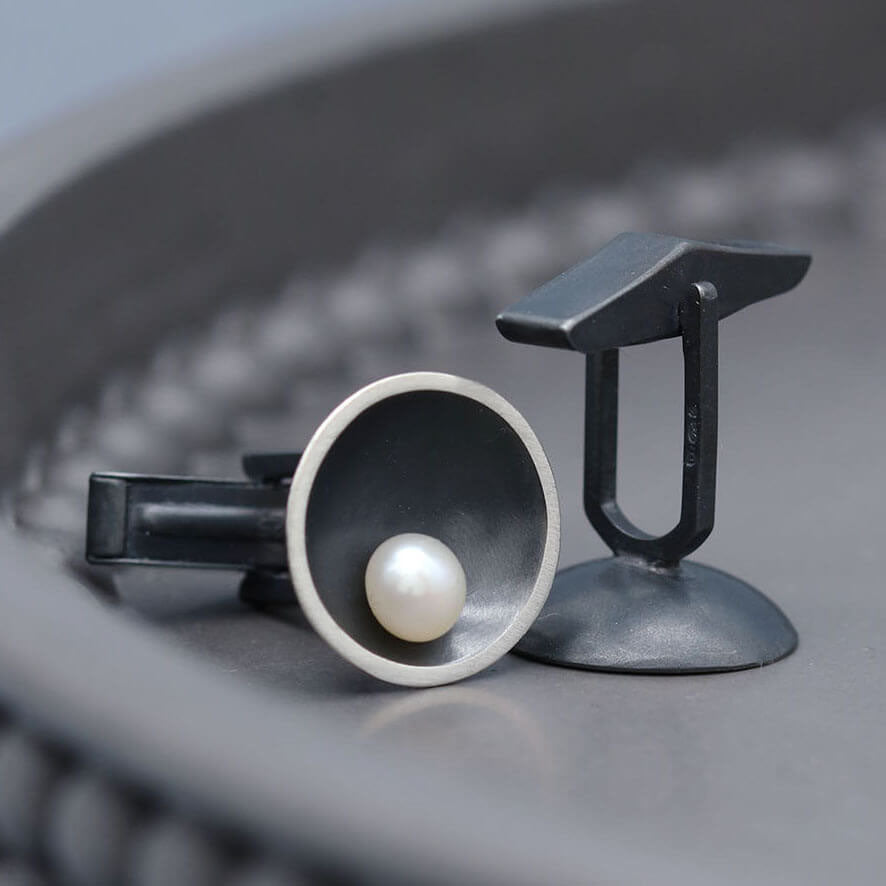 Close up of handmade black pearl cufflinks showing the contrast between oxidised sterling silver and lustrous freshwater pearls.