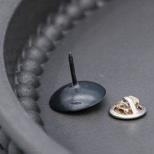 Black pearl lapel pin handcrafted in sterling silver with a polished freshwater pearl centre.