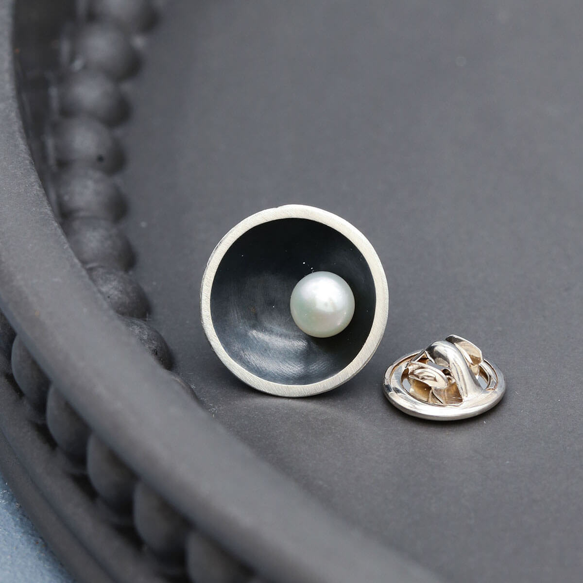 Handmade black pearl pin for men inspired by Art Deco design and traditional silversmithing techniques.