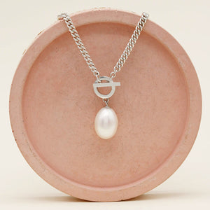 Handmade sterling silver toggle pearl necklace with a large genuine freshwater pearl and chunky curb chain on a pink ceramic dish.