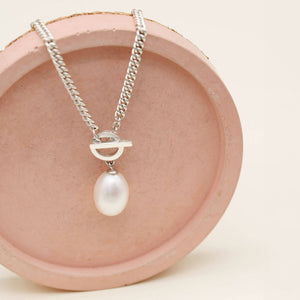 Sterling silver toggle pearl necklace displayed on a pink ceramic dish, highlighting the large freshwater pearl and chunky chain.