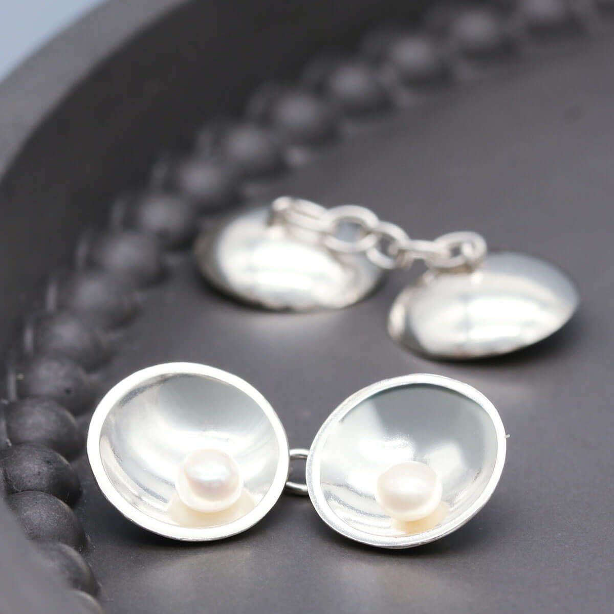 Sterling silver double-sided pearl cufflinks featuring freshwater pearls on both sides and a chain connection.