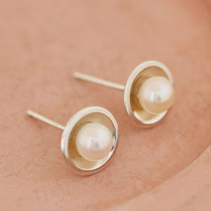 Close-up of real pearl stud earrings on a pink dish, simple Pearl Earrings for women crafted as real pearl stud earrings.