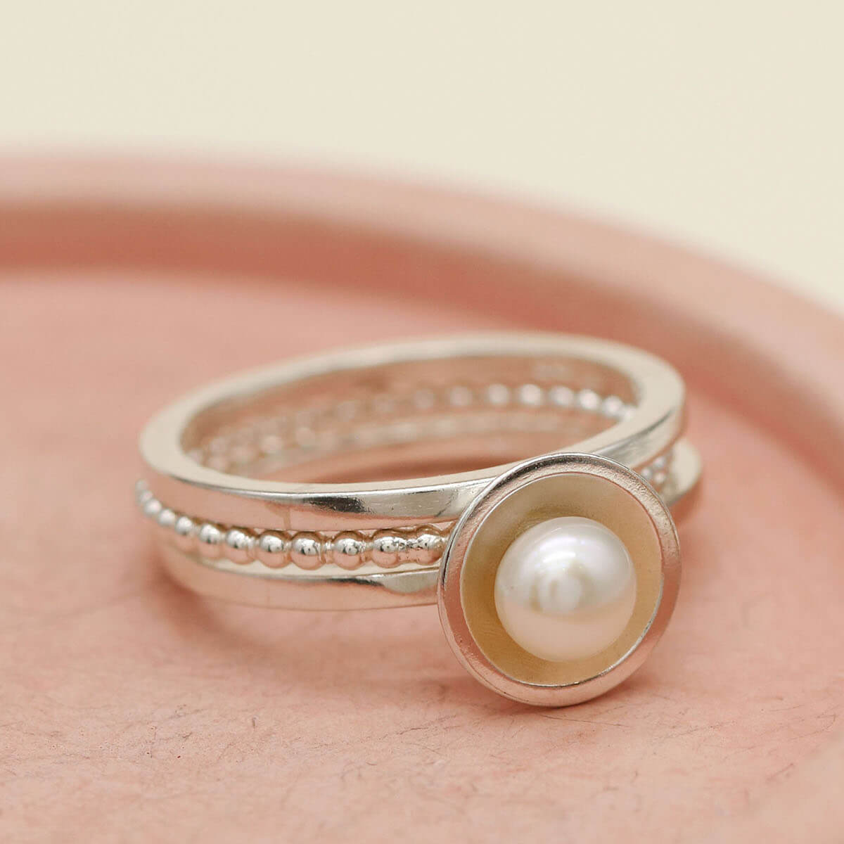 Handmade pearl stackable rings arranged together on a pink ceramic dish