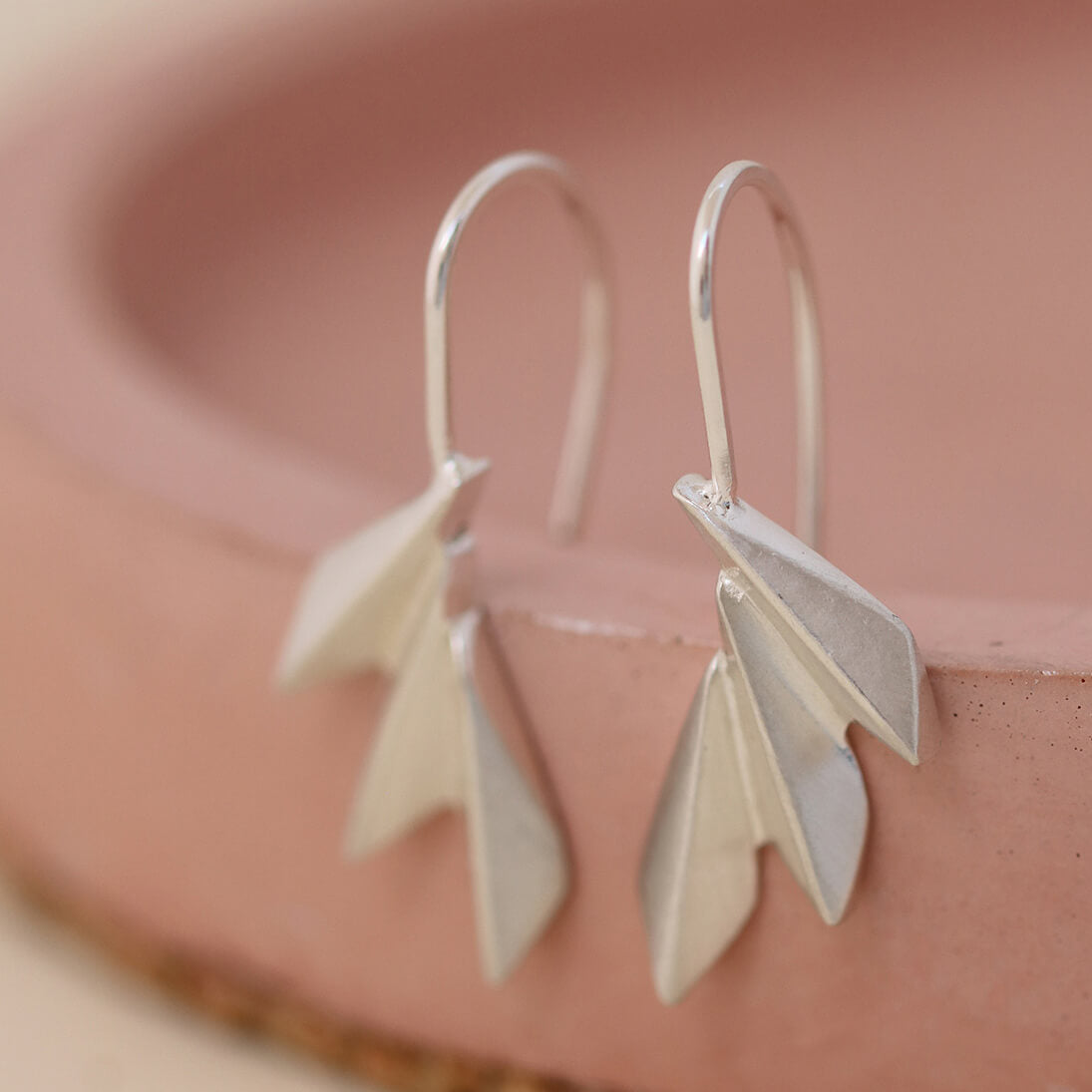 Sterling silver art deco drop earrings arranged on a soft pink dish; elegant fan drop earrings perfect for anniversaries and bridesmaid gifts.