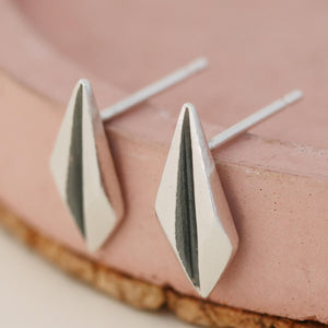 Silver art deco earrings displayed on a pink dish showing geometric design and oxidised detail.