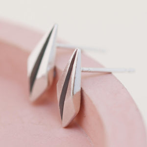 Pair of silver art deco earrings on pink dish showing side profile of art deco earrings studs.