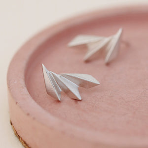 Art deco fan earrings on a pink dish with emphasis on the handcrafted shape.