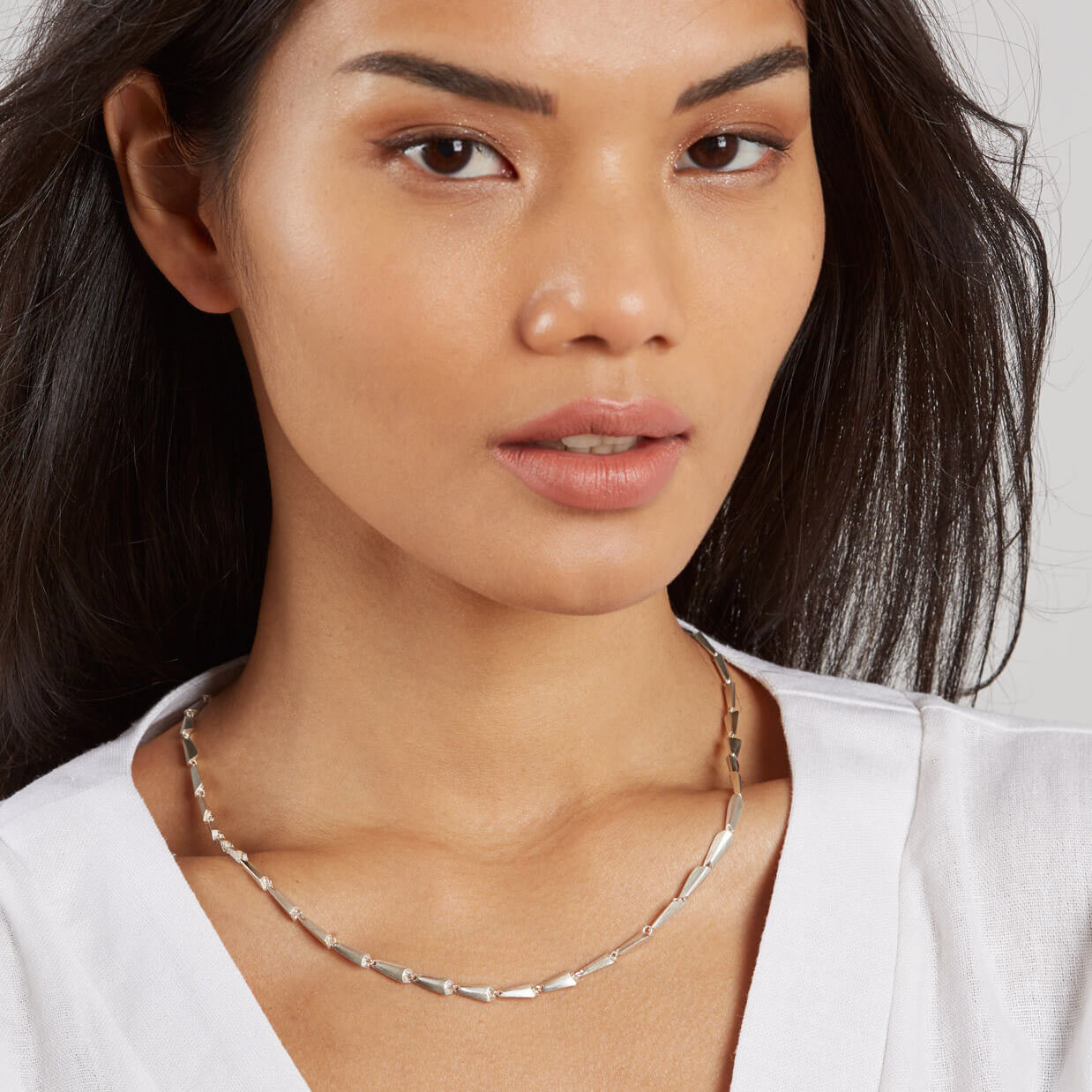 Model wearing the silver link necklace with a V-neck top, showcasing how the contemporary necklace sits beautifully for day or evening wear.