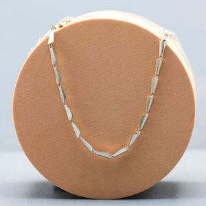 Art Deco silver link necklace displayed on a deep blue background, showing the repeating geometric link design
