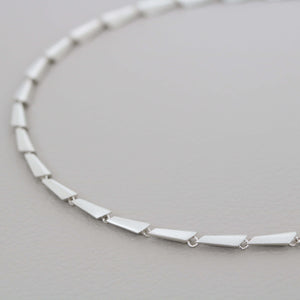 Sterling silver link necklace photographed close up, showing the individually carved and cast geometric links