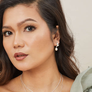 Close-up of earrings worn with loose hair, highlighting the sculptural Art Deco silver fan and teardrop pearl for elegant everyday wear.