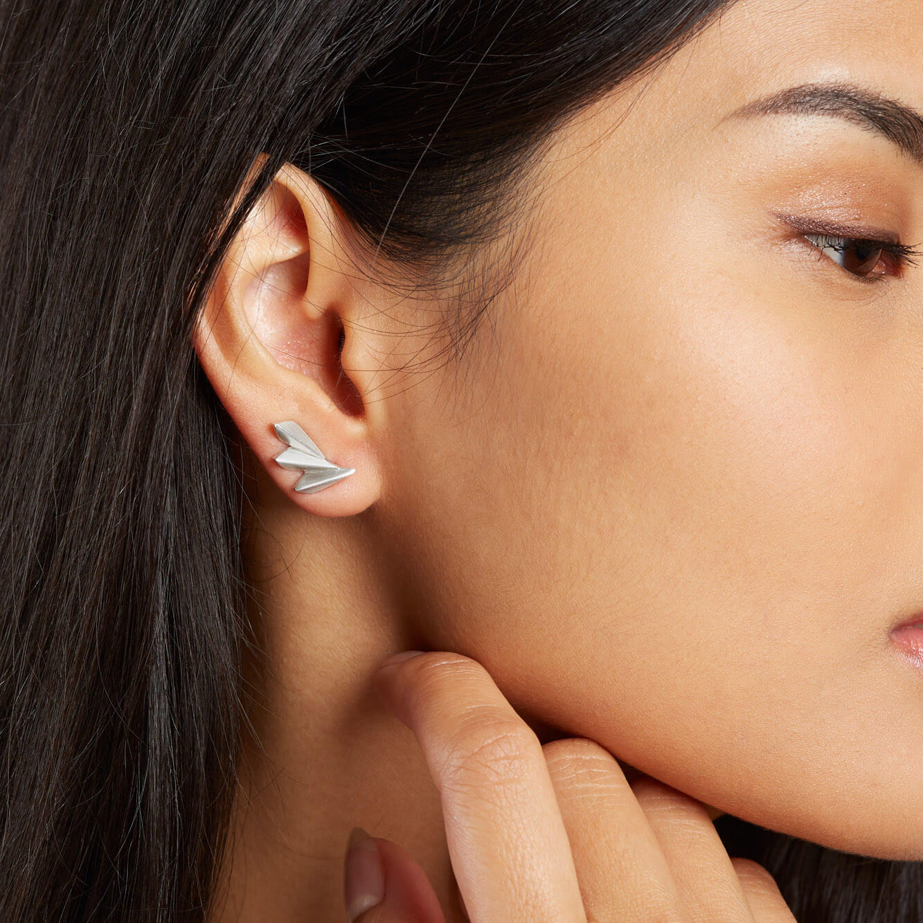Close-up of model wearing art deco fan earrings styled as subtle ear climbers.