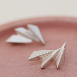 Art deco silver earrings displayed on a pink dish, showing the sculptural curved fan design.