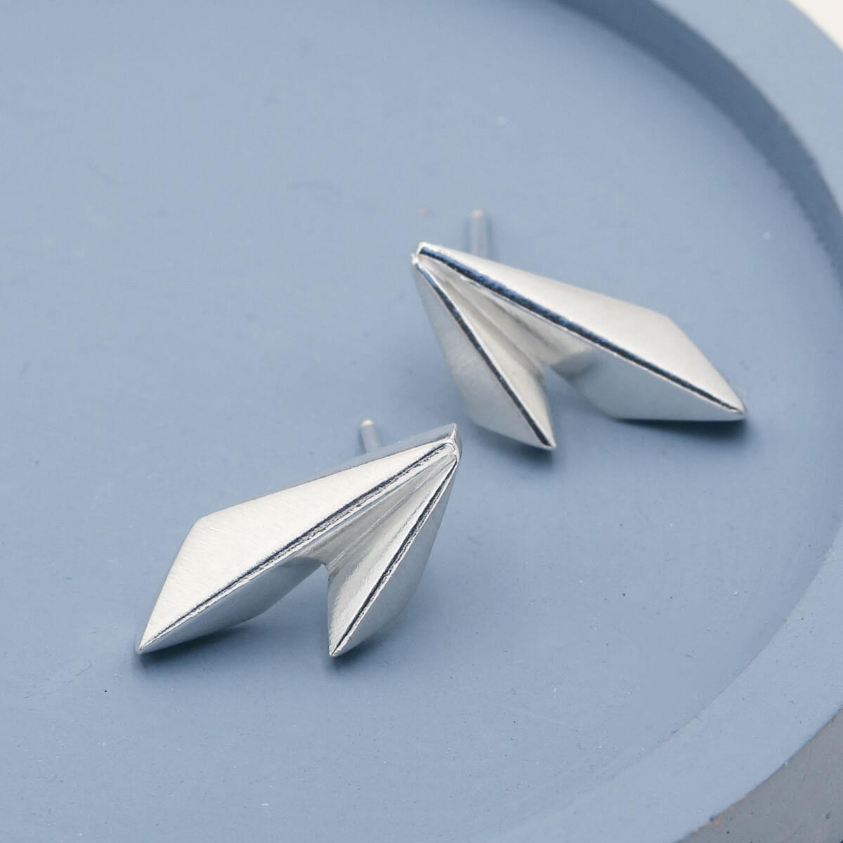Close-up of handmade Art Deco earrings showing the overlapping kite shapes and matte silver finish
