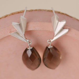 Smoky quartz earrings resting on a ceramic dish showing the silver fan detail and warm gemstone tone; modern art deco statement earrings for her.