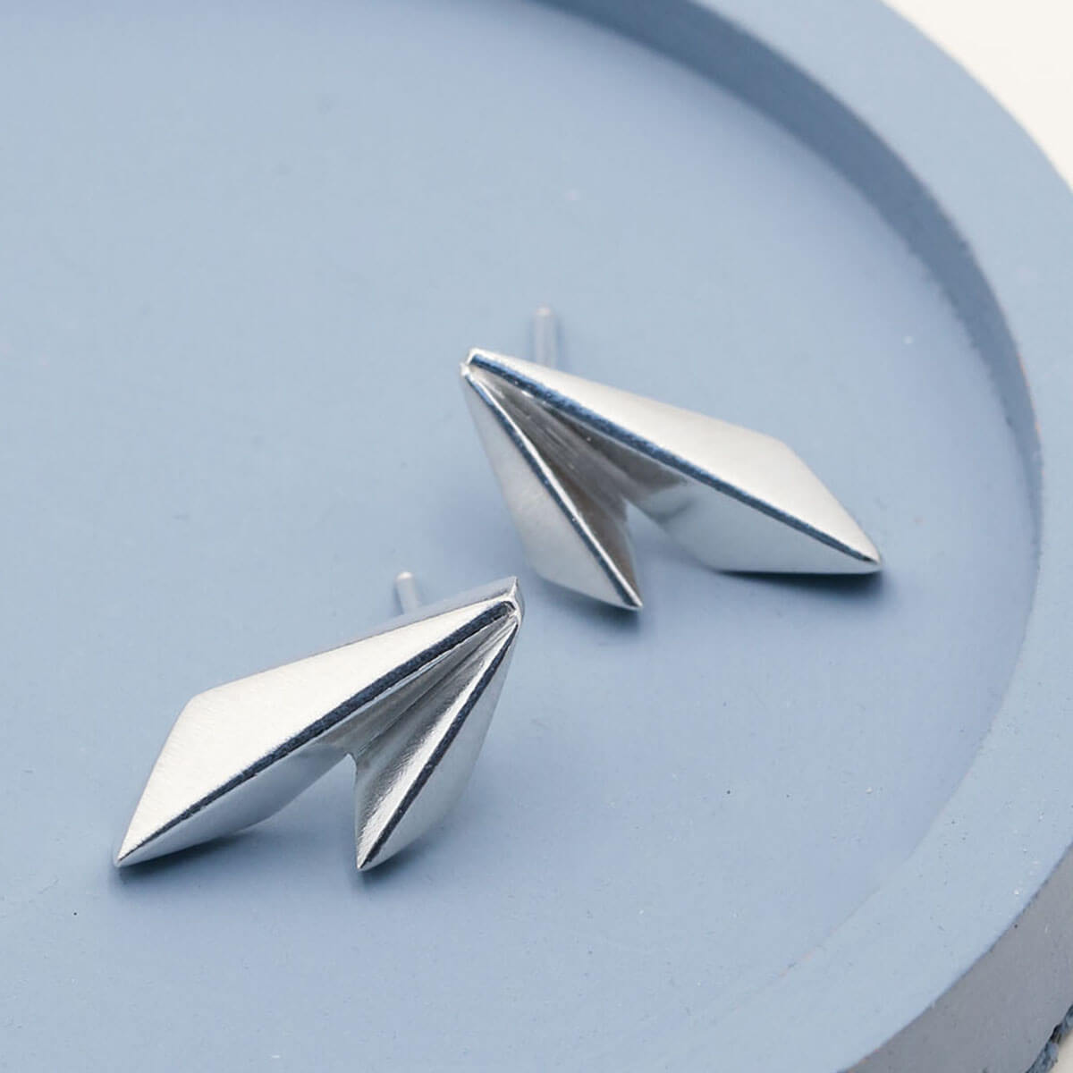 Deco Double Kite stud earrings in solid sterling silver, geometric Art Deco design on a deep blue dish