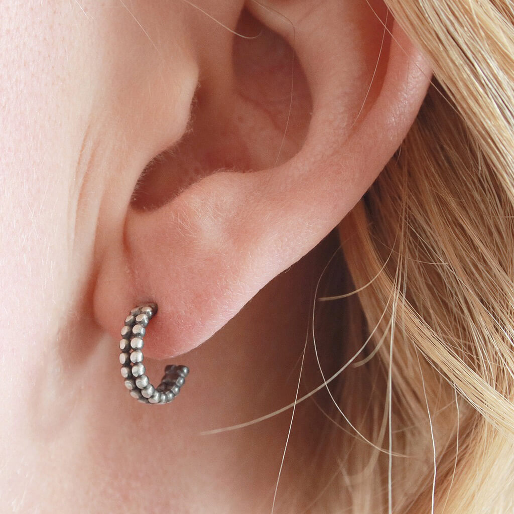 Silver and black hoop earrings worn in the ear, little black hoop earrings styled for everyday wear