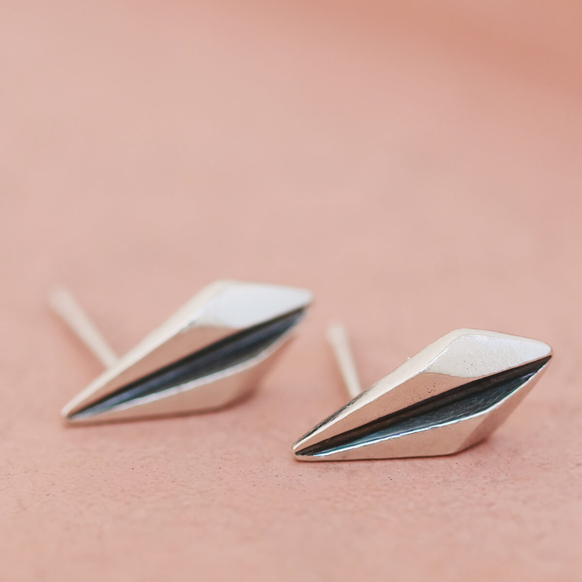 Silver art deco earrings resting on pink dish with focus on oxidised black centre.