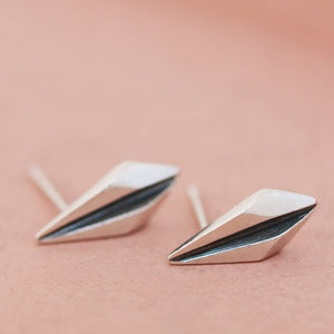 Silver art deco earrings resting on pink dish with focus on oxidised black centre.