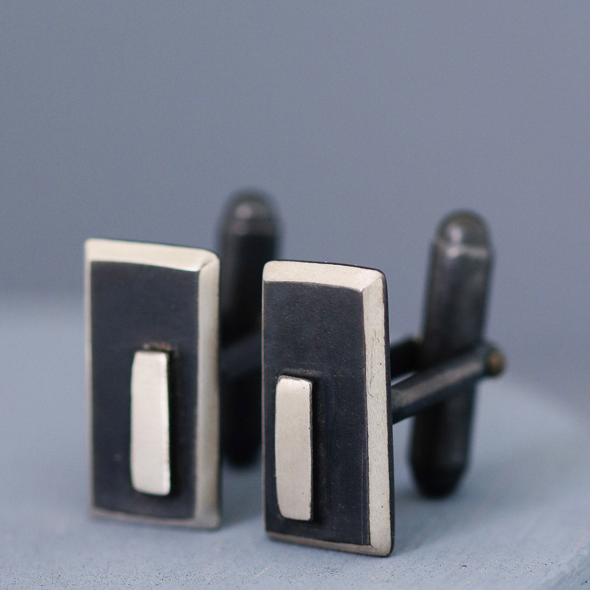 Close-up of black and silver cufflinks on a deep blue background, showing their geometric Art Deco design — perfect special gifts for husband’s birthday.
