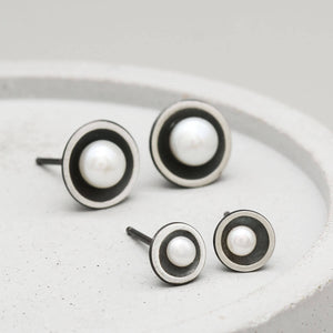 Small Petite pearl stud earrings displayed alongside the Classic size to highlight their delicate proportions.