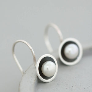 Handmade black pearl drop earrings with genuine freshwater pearls in oxidised sterling silver displayed on a grey ceramic dish.