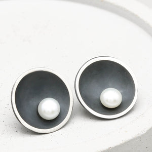 Handmade Signature Black Pearl Stud Earrings in oxidised sterling silver with genuine freshwater pearls displayed on a grey ceramic dish.
